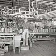 Black and white historical shot of workers on product assembly line packagine Oronite products.