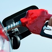 Hand on gas pump nozzle fueling vehicle.