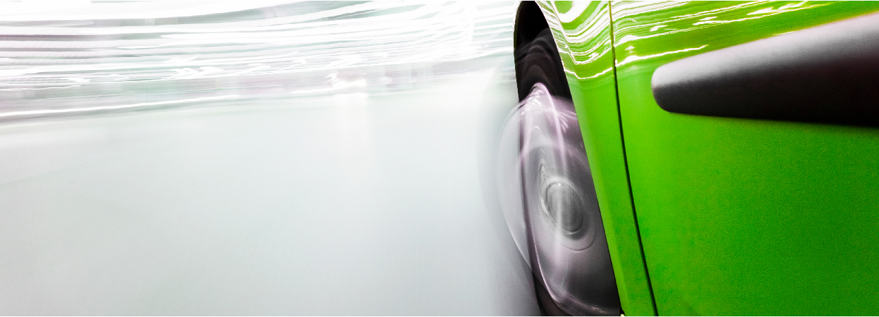 Print Close-up of front left wheel well area of green automobile with motion blur.